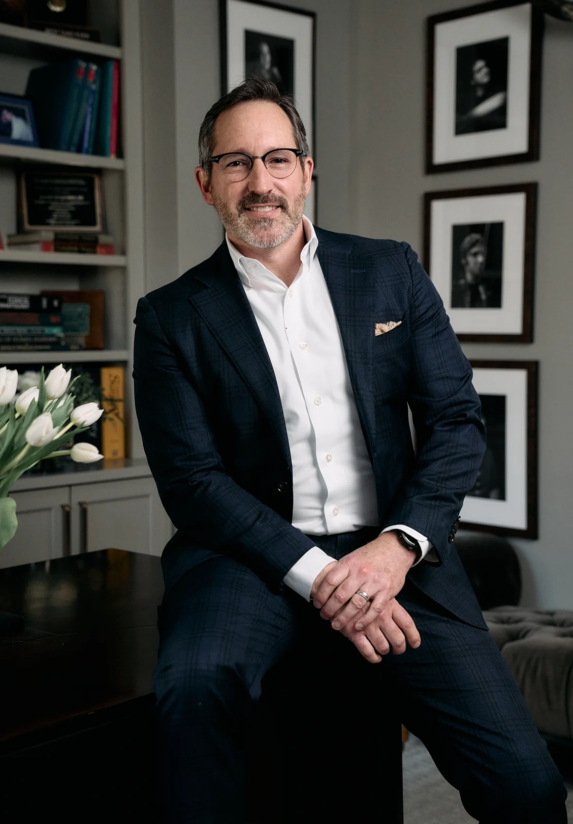 Doctor Morganstern MD in navy suit sitting in modern office with framed artwork and bookshelves - in Wayne, PA