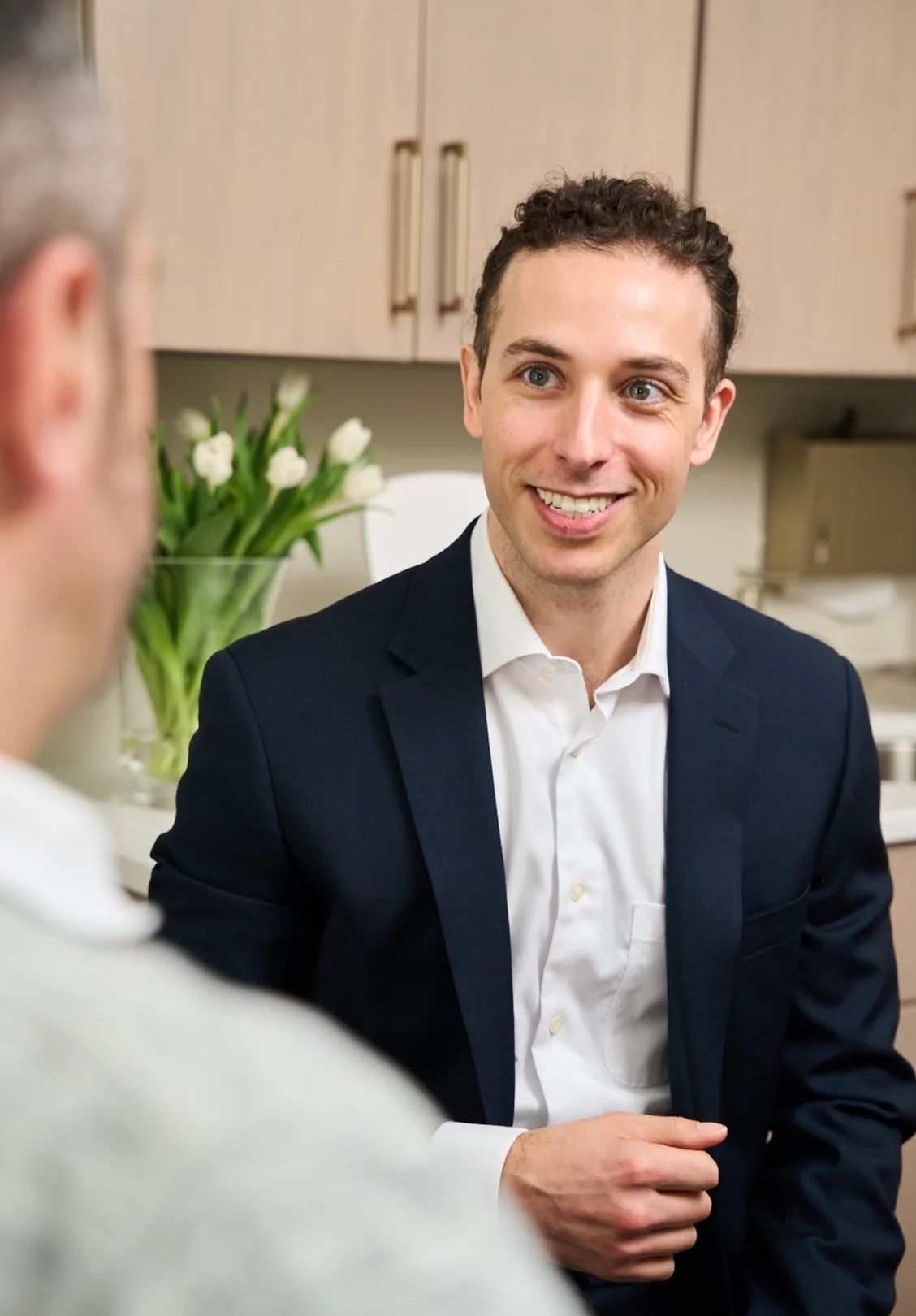 Doctor wearing suit smiling at patient in a modern medical office setting. - in Wayne, PA