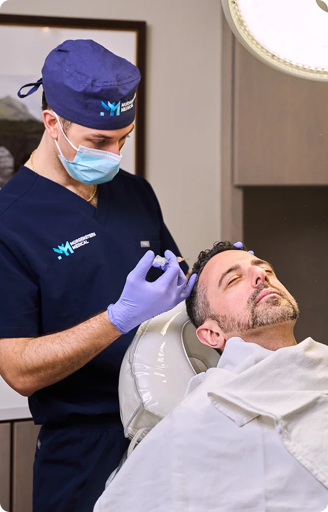 Doctor Marc Govert in blue scrubs and mask examining male patient in dental chair during checkup procedure - hair in Wayne, PA