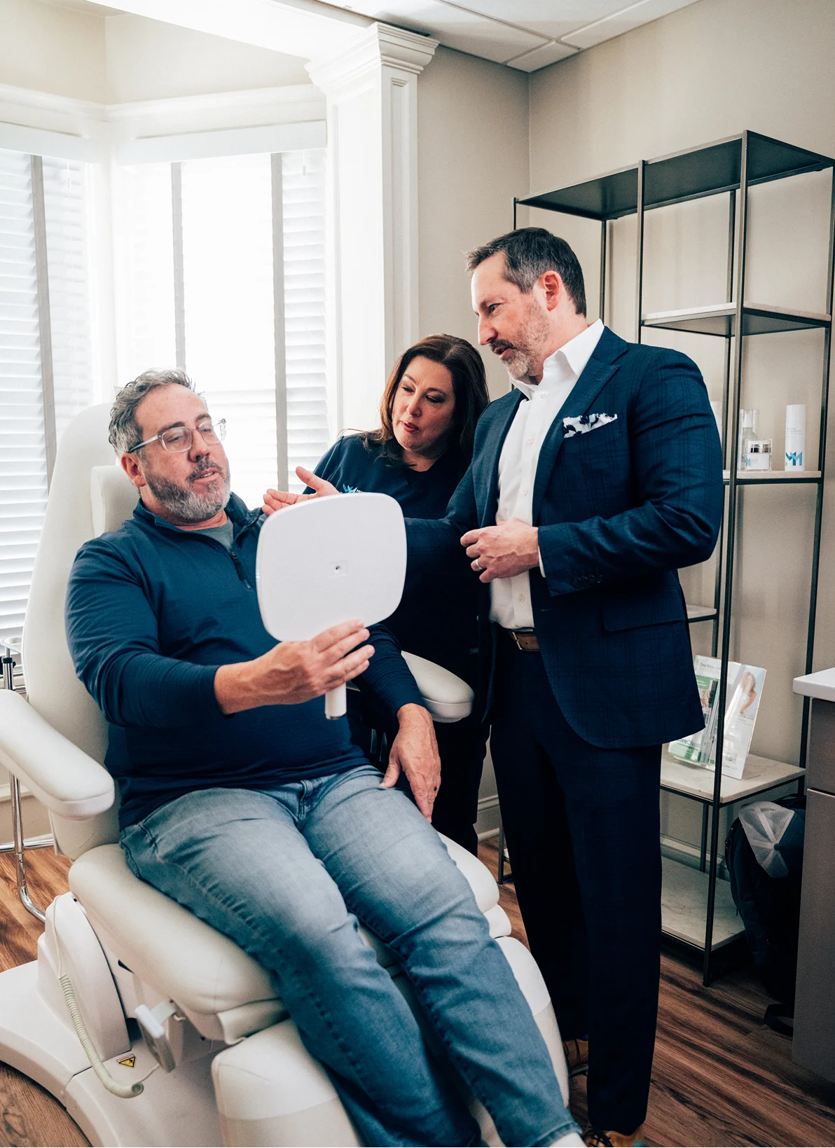 Doctor Morganstern MD and nurse looking at male patient in a medical chair. The patient is looking into a hand held mirror. - in Wayne, PA