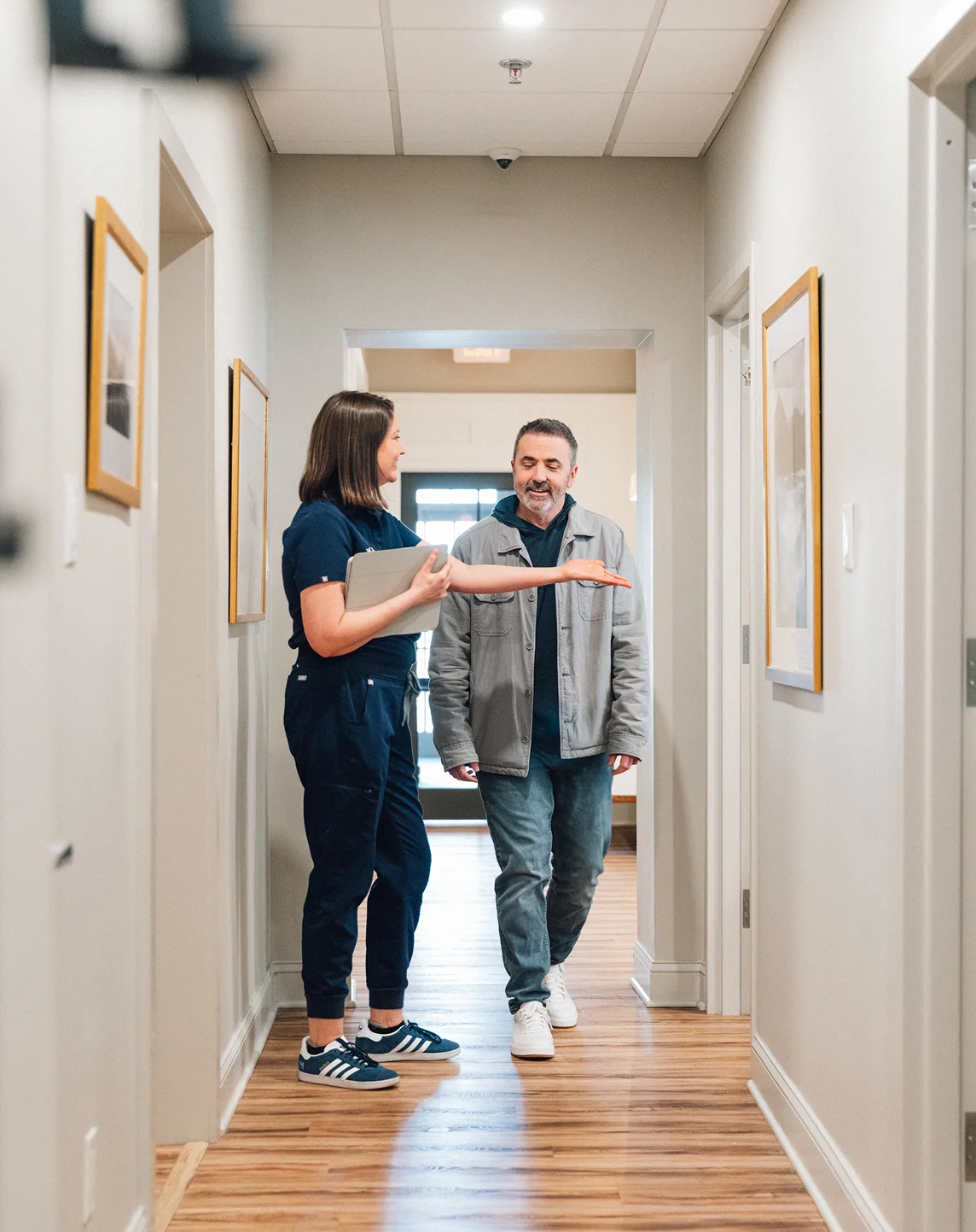 Healthcare professional consulting with patient in modern medical office hallway - in Wayne, PA