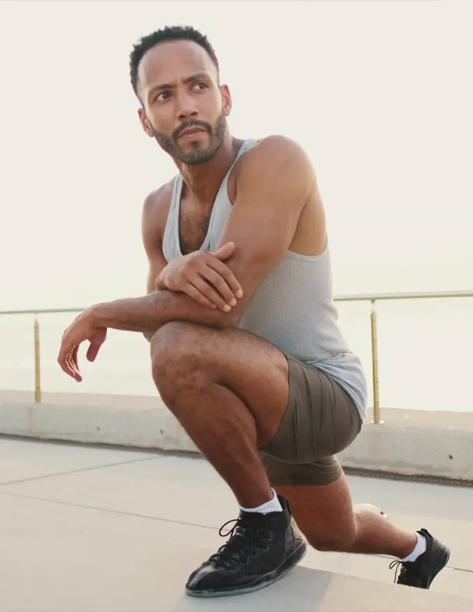 Athletic man in gray tank top and shorts demonstrating single-leg squat exercise outdoors - thigh lift in Philadelphia ,PA